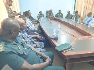 Mr. Samuel Amadu Basintale in camouflage and military cup in a handshake  and his team at one of the border